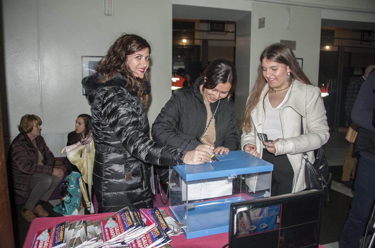 Tres asistentes al teatro votan en el reverso de su entrada. pakopí