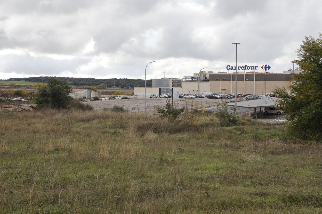 Terrenos del futuro parque comercial de medianas superfies con los aparcamientos de Carrefour al fondo. 