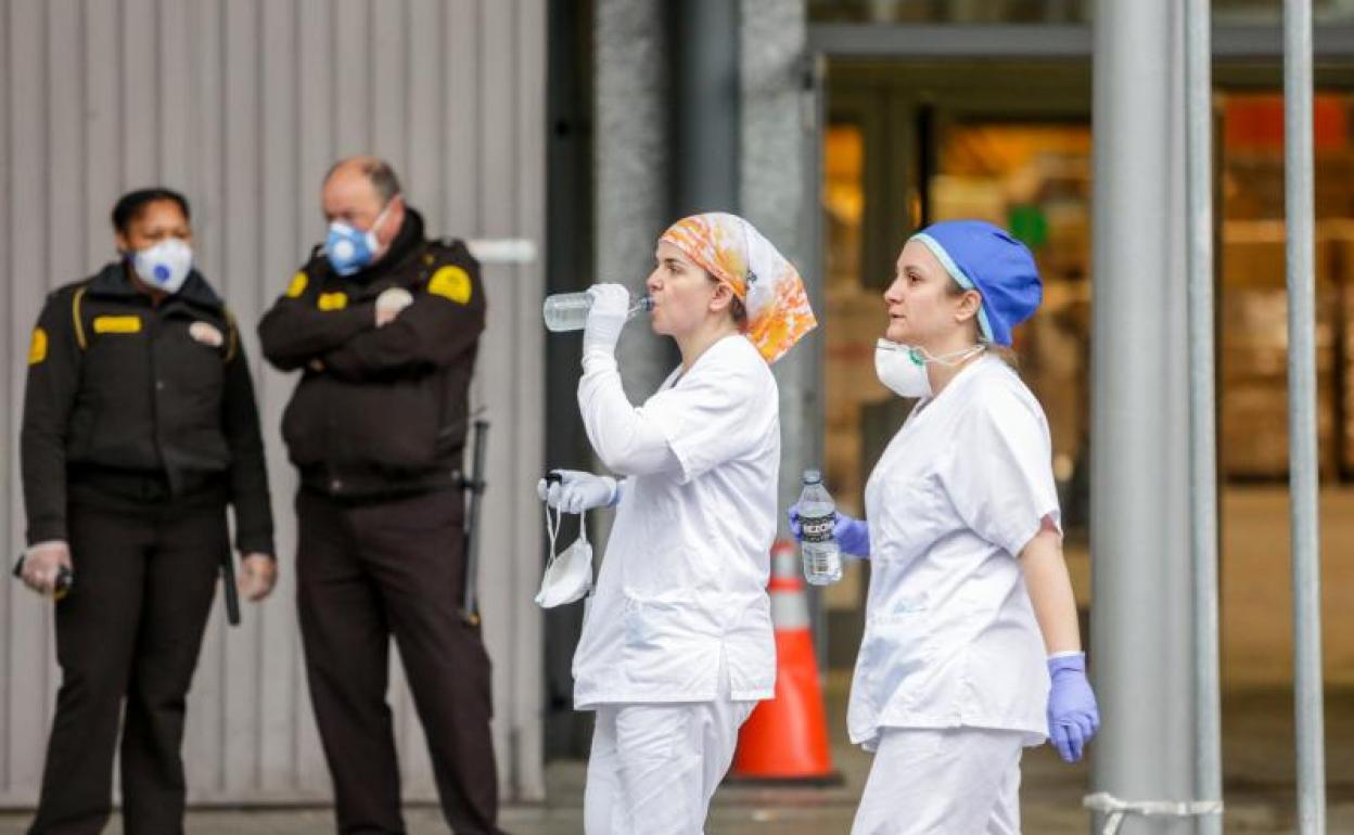 Dos sanitarias protegidas con mascarilla y guantes junto a dos guardias de seguridad en IFEMA 