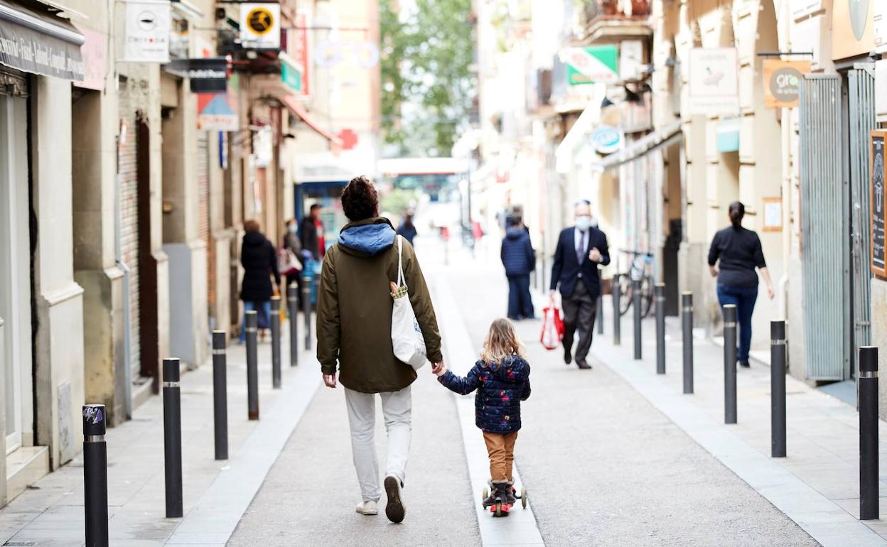 Un hombre y una niña caminan por el barrio de Gracia de Barcelona. 