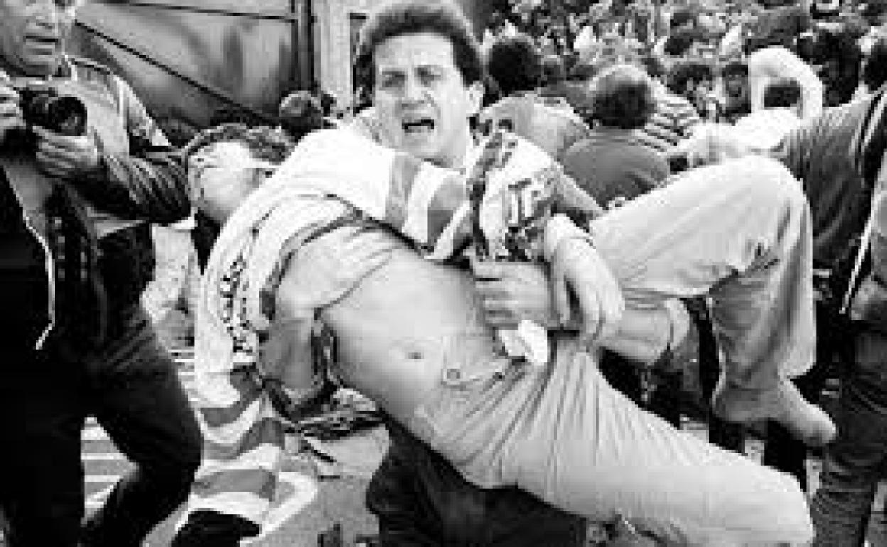 Un aficionado, con un joven en brazos, tras la avalancha en Heysel. 