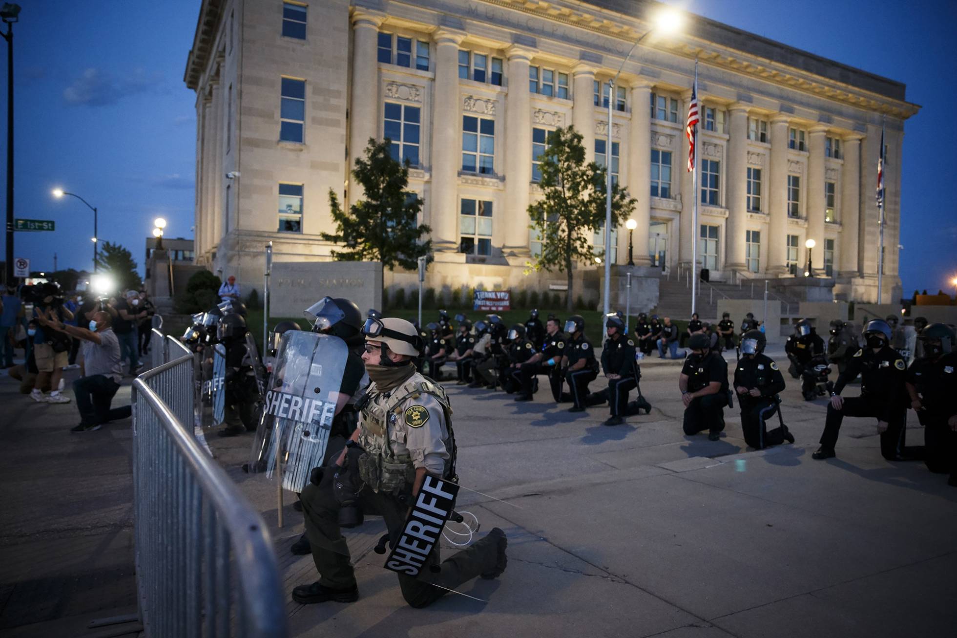 Agentes de policía se arrodillan durante una manifestación frente a la sede de la Policía de Des Moines, Iowa