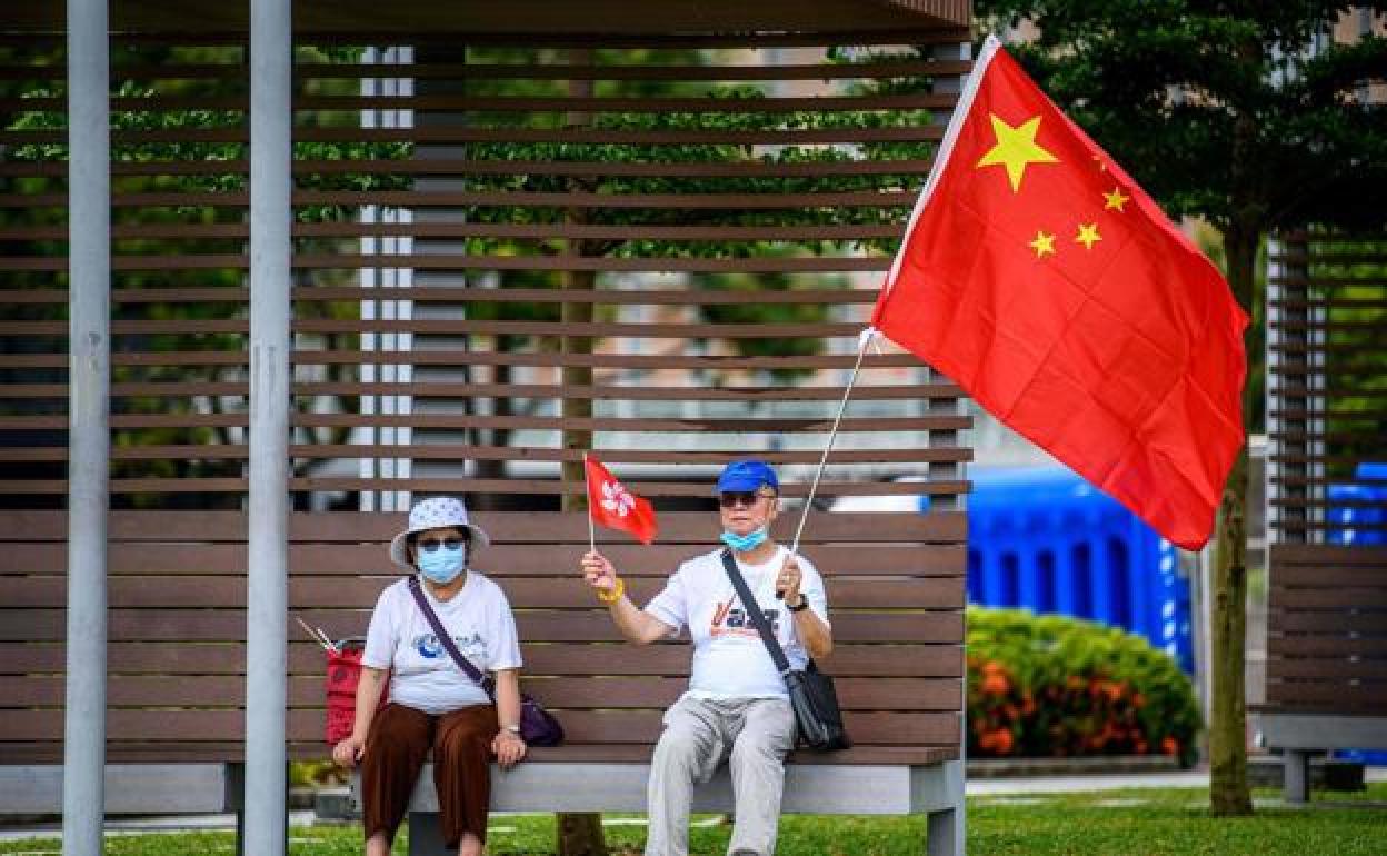Dos personas con las banderas china y de Hong Kong.