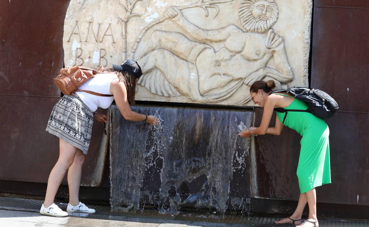 Dos jóvenes se refrescan en una fuente en Mérida.