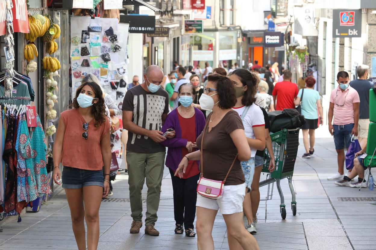 Viandantes protegidos con mascarillas por la calle Santa Eulalia. 