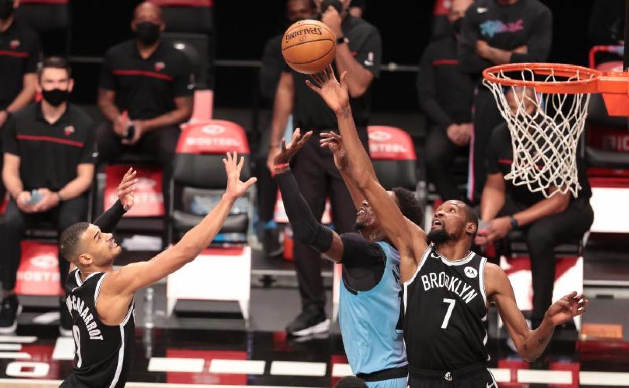 El alero de los Nets Kevin Durant (7) y Jeff Green (8) luchan por un rebote contra el pívot de los Heat Bam Adebayo 