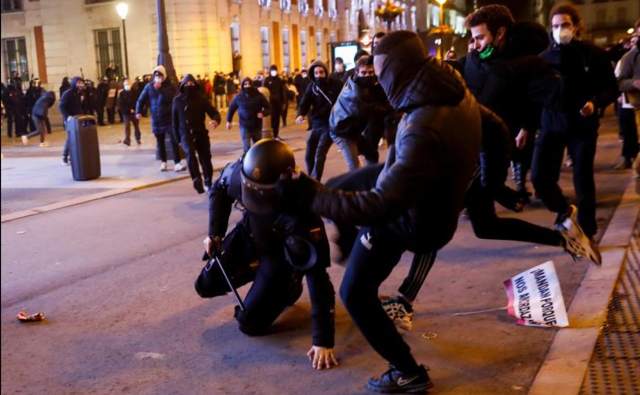 Varios manifestantes apalean a un policía en la Puerta del Sol de Madrid.