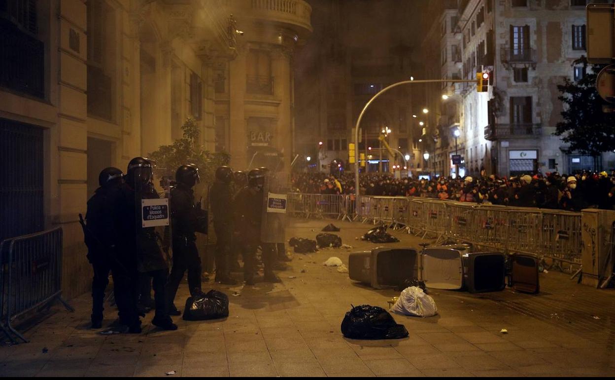 Varios Mossos soportan los impactos de objetos lanzados contra ellos por los manifestantes en Barcelona.