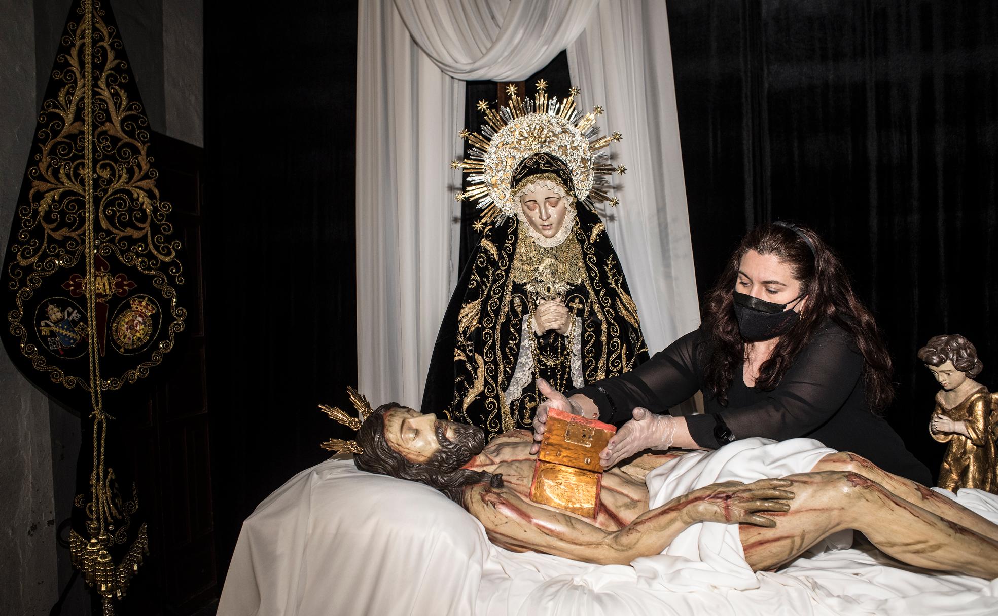 La hermana mayor del Santo Entierro, Mamen Gutiérrez, abriendo el rosario del pecho del Yacente, que está junto a la Virgen de las Lágrimas, en la iglesia de San Agustín. 