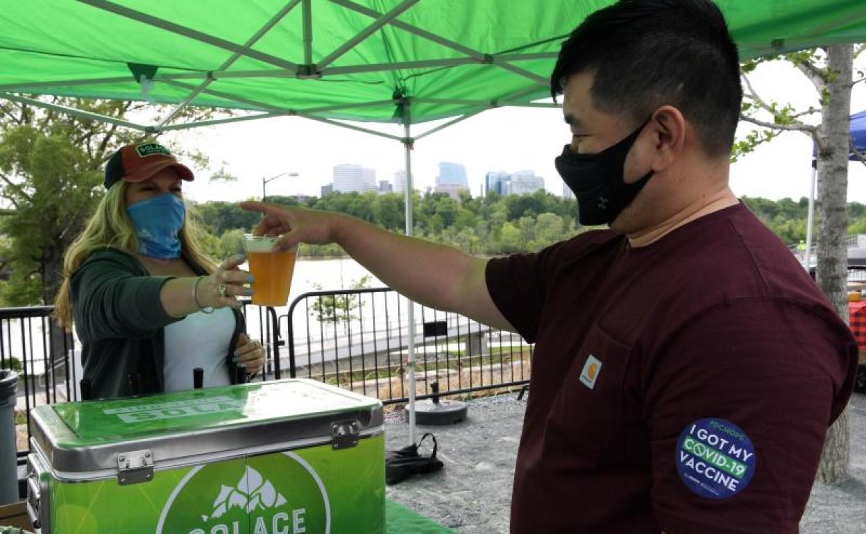 Un hombre recibe una cerveza como recompensa por haberse vacunado contra la covid.