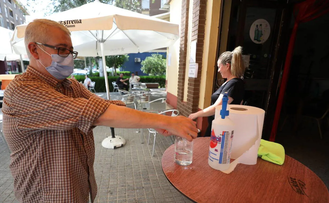 Un hombre echándose gel hidroalcohólico en las manos antes de entrar en un bar de Márida.