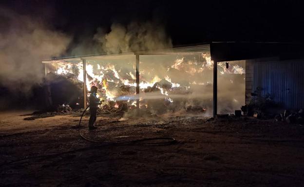 Un bombero del Sepei tratando de apagar las pacas incendiadas en el interior de una de las naves. 