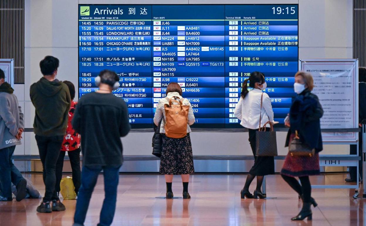 Viajeros japoneses observan el panel de un aeropuerto tras la prohibición de reingreso de extranjeros. 