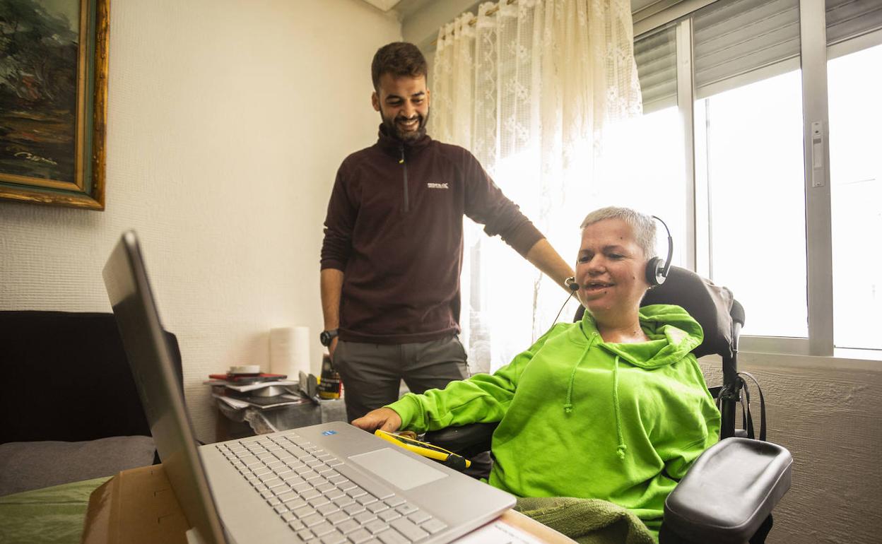 Chari Sánchez en su casa con los dispositivos para su trabajo de teleoperadora y su asistente Ernesto Ríos. 