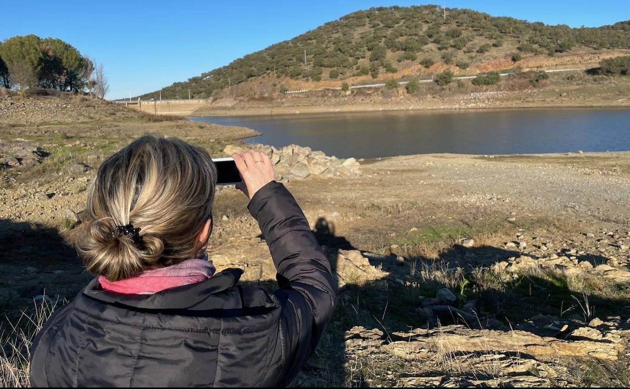 Una mujer de Monesterio fotografía el embalse de Tentudía, que solo tiene agua hasta febrero para los pueblos que beben de él. 