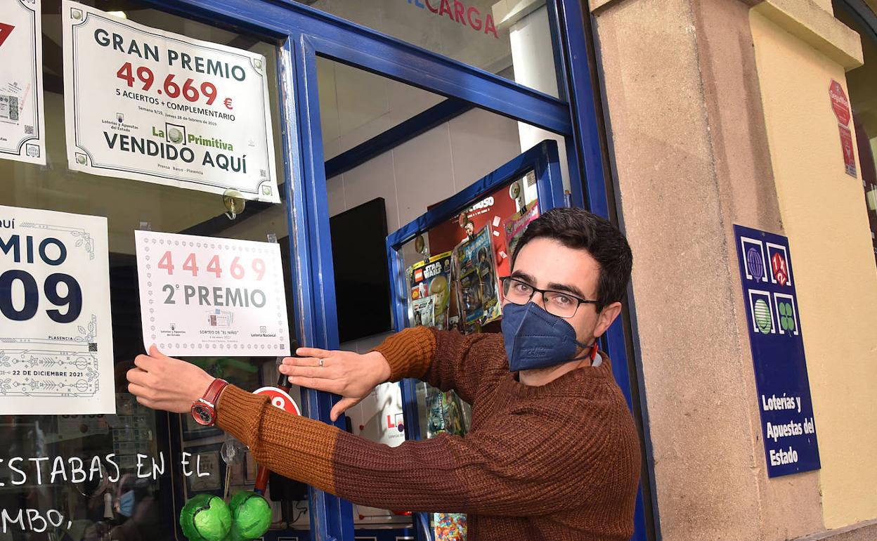 Javier Díaz coloca el cartel con el número premiado en el punto de venta mixto de la calle Talavera. 