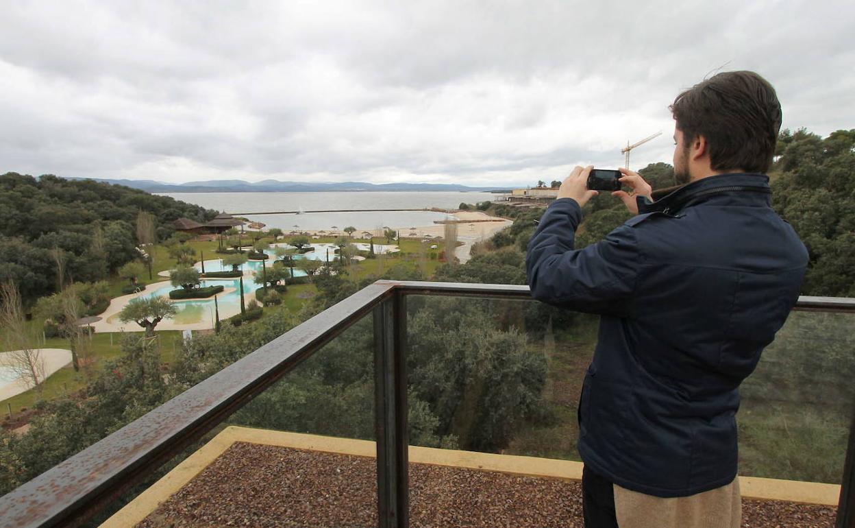 Un visitante del complejo fotografía la zona de playa artificial, con el embalse de Valdecañas al fondo.