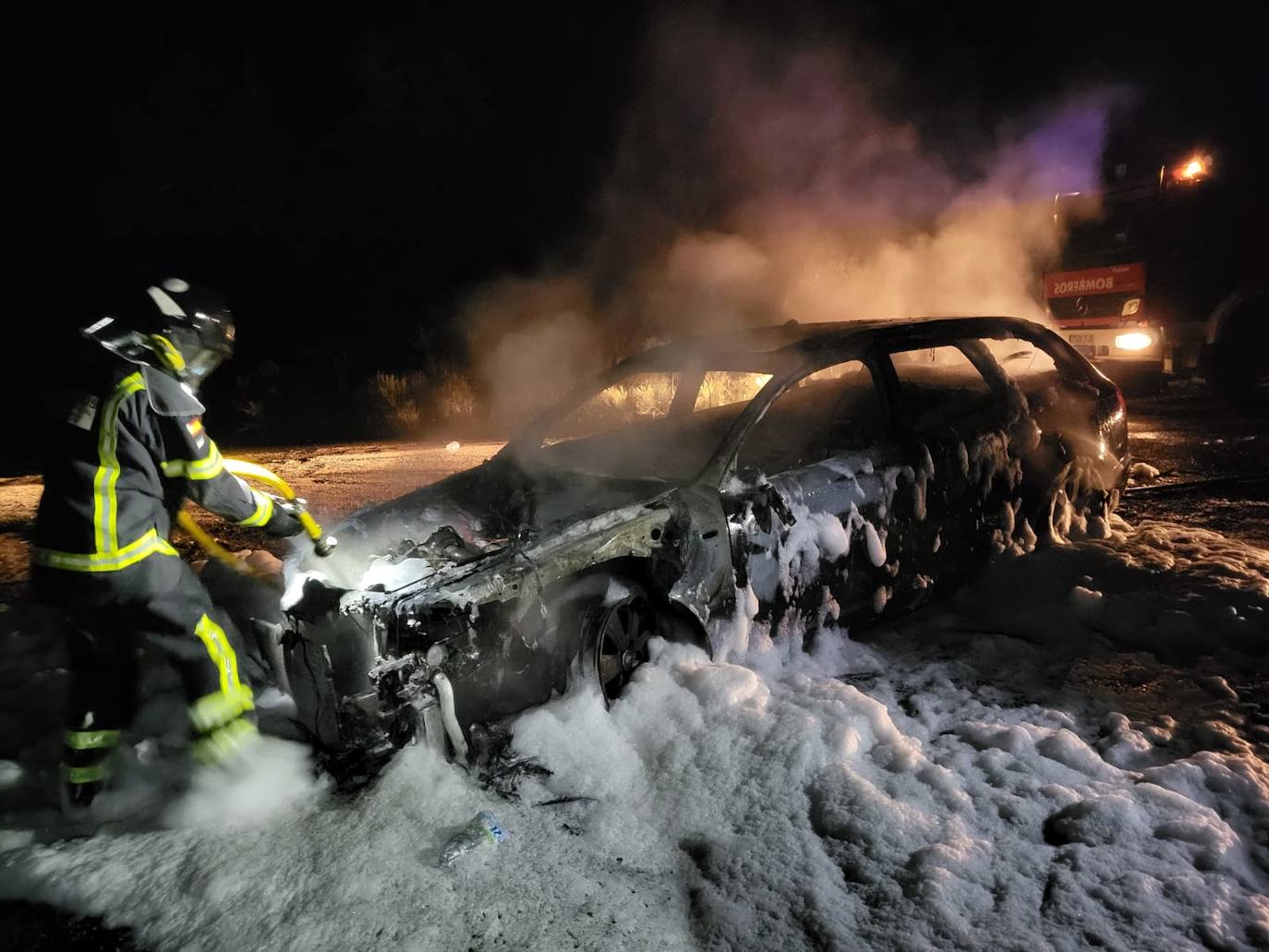 Un bombero de la Diputación de Badajoz apaga el turismo incendiado en la EX-302. 