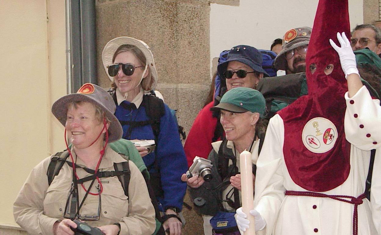 Imagen de un grupo de turistas junto a un integrante de la cofradía de la Sagrada Cena, en Cáceres. 
