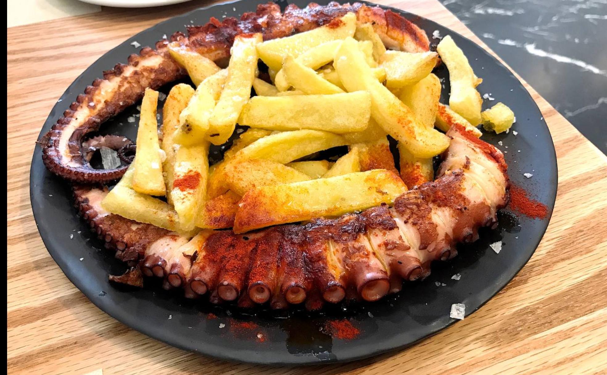Pulpo a la brasa con generosa ración de patatas fritas.