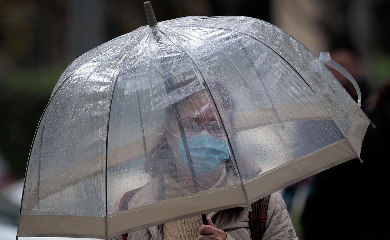Una mujer se protege de la lluvia con un paraguas