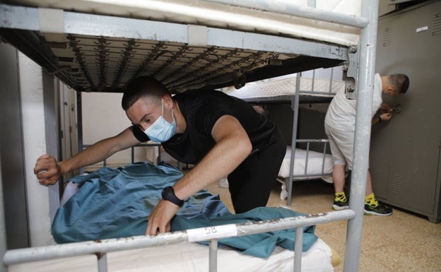 Los nuevos alumnos preparan sus camas en el dormitorio asignado.