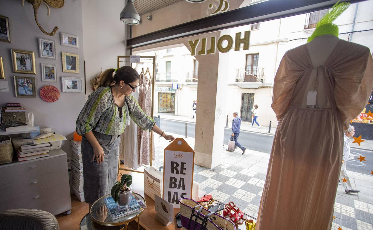 Patricia Mejías, socia de la tienda de moda Saks, muestra el cartel de rebajas de su establecimiento, donde empezaron el pasado día 16. 