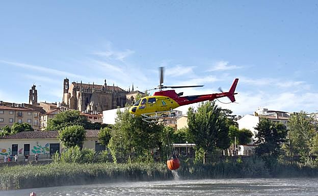 Un helicóptero del Infoex coge agua del río Jerte con la catedral al fondo. 