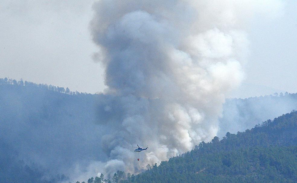 Uno de los heliópteros arroja agua ante una inmensa columna de humo. 