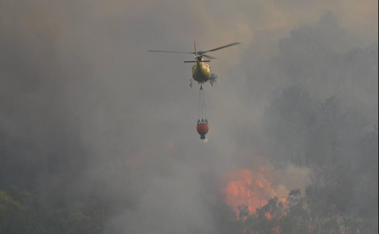Un helicóptero se dirige hacia las llamas cerca de Casas de Miravete.