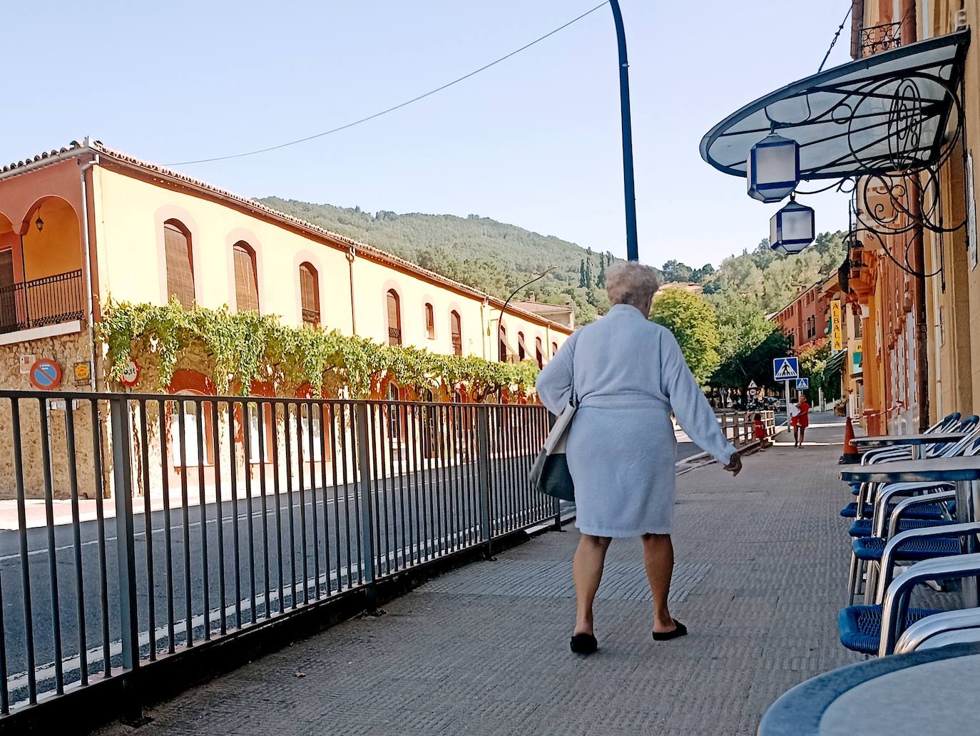 Con albornoz por la calle principal de Baños de Montemayor, a la izquierda el Hotel Eloy con su parra de 144 años.