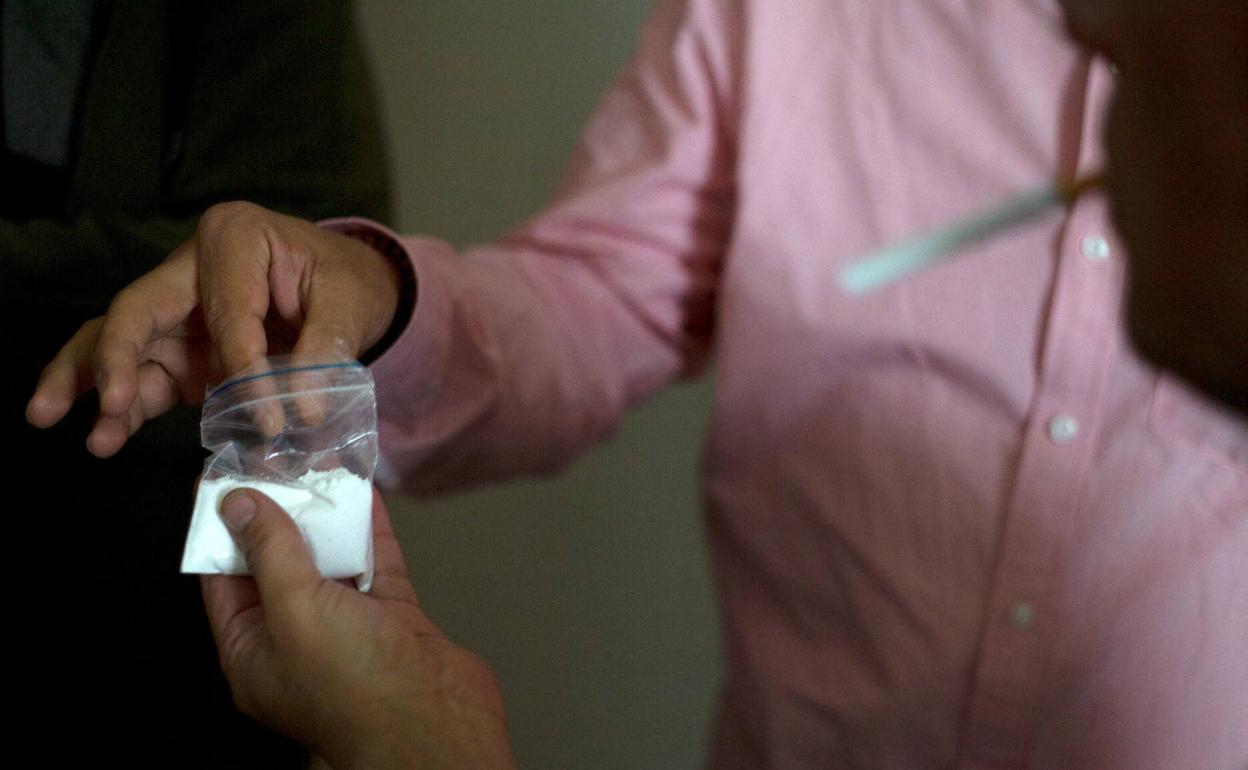 Un cocainómano, con una bolsa de la sustancia en la mano. 