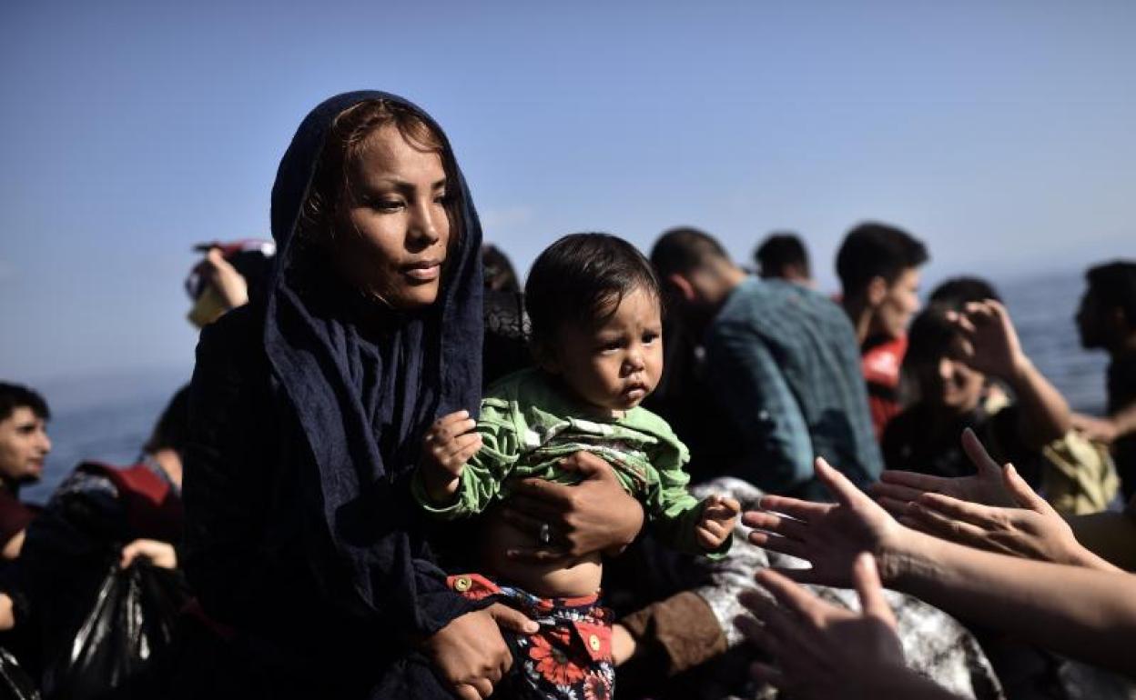 Una mujer migrante sostiene a un niño mientras refugiados y migrantes llegan a la isla griega de Lesbos después de cruzar el mar Egeo desde Turquía. 