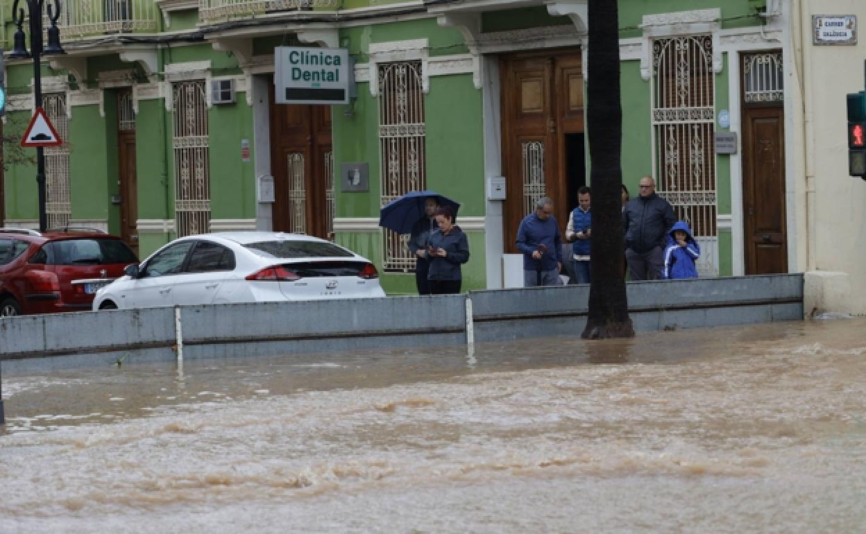 Una valla provisional trata de contener el agua en una calle de Torrent. 