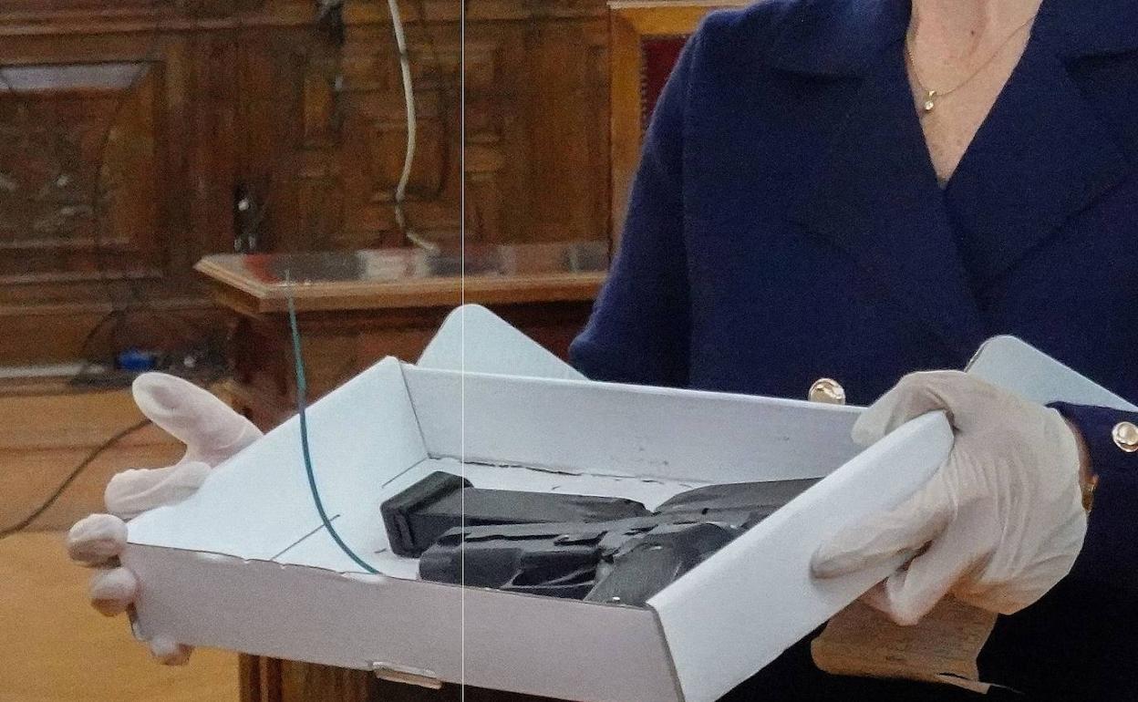 Una funcionaria muestra la pistola y el cargador al tribunal.