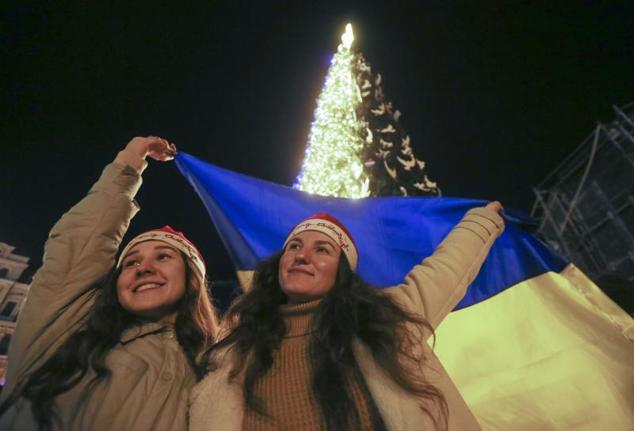 Dos ucranianas celebran en Kiev la entrada del Año Nuevo con una bandera de su país en plena guerra.