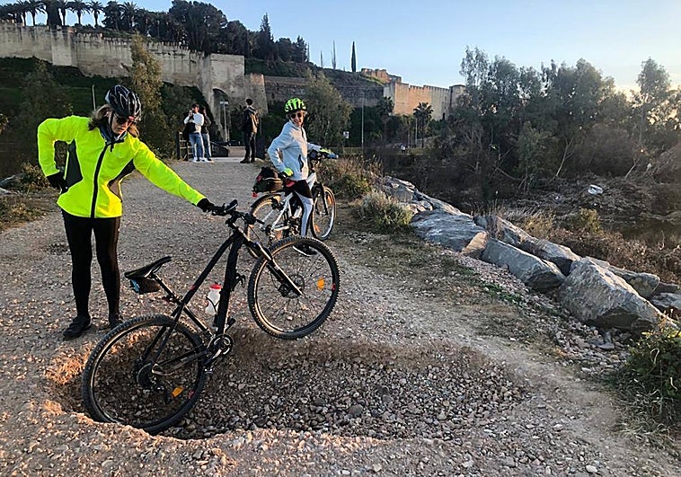 Una ciclista enseña el socavón junto a la pasarela de entrada.