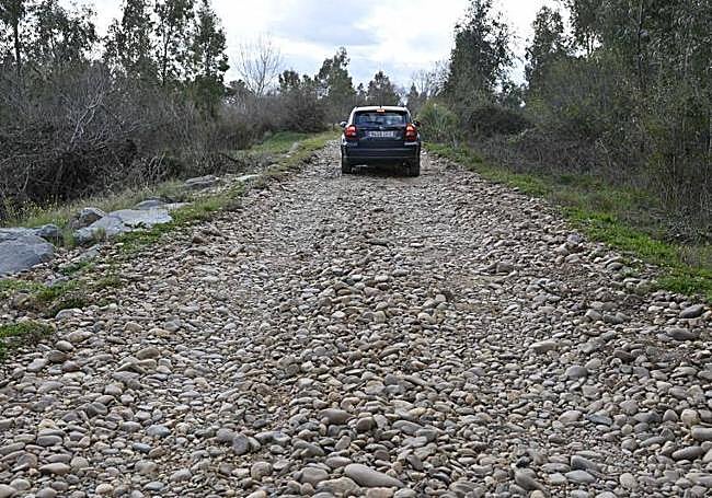 Un vehículo circula sobre piedras en el camino a la pasarela por la margen derecha.