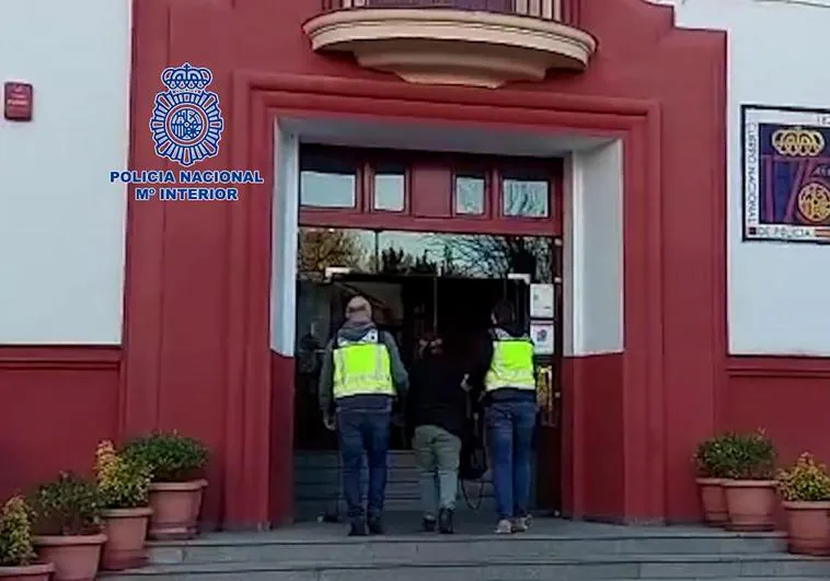 La detenida entra escoltada por dos agentes a la comisaría de la Policía Nacional en Badajoz.