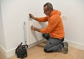 Un operario instala un contador individual en un radiador.