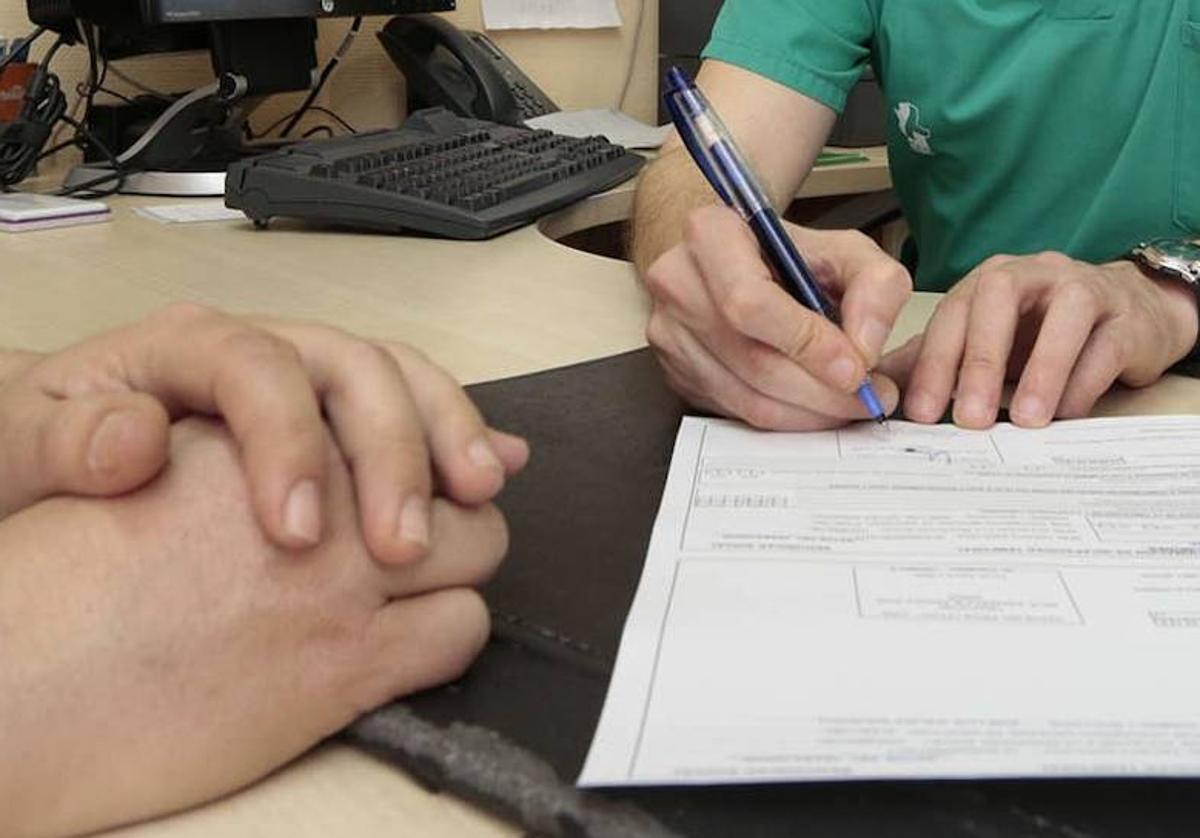 Imagen de archivo de un médico firmando una baja laboral en el SES