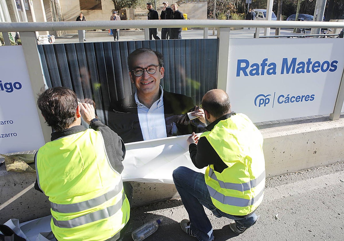 Dos operarios colocando carteles de Rafael Mateos en la avenida Clara Campoamor el pasado mes de marzo.