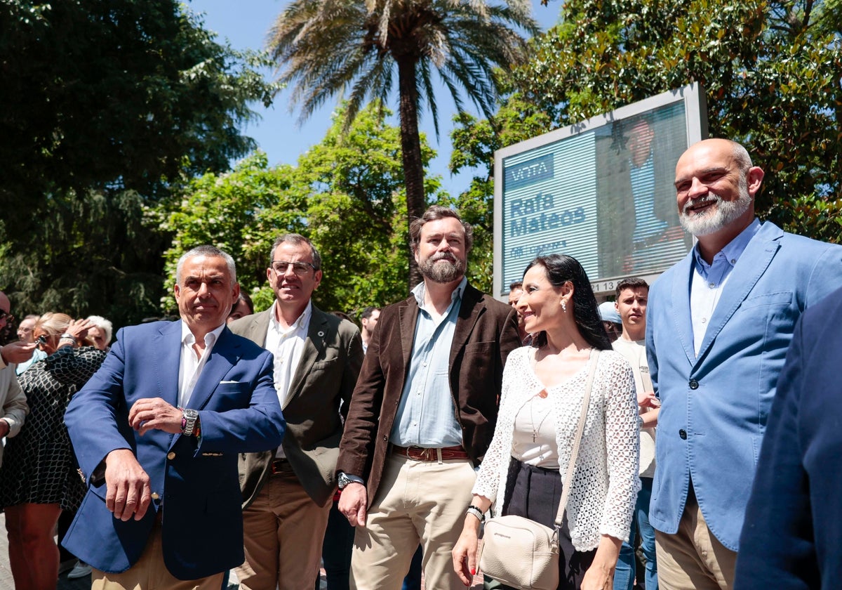 Dirigentes de Vox en Cáceres delante de un cartel electoral del PP.