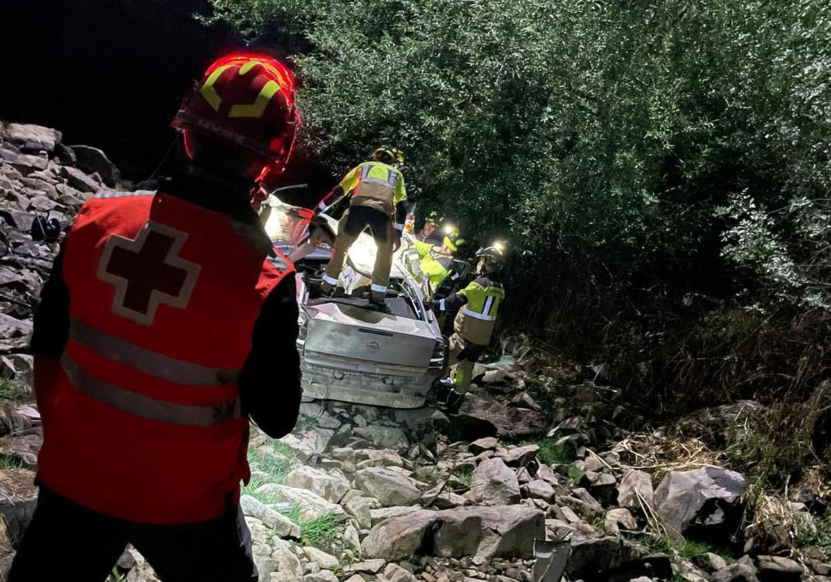 Un efectivo de Cruz Roja observa los trabajos de los bomberos para rescatar los cuerpos del Opel Vectra siniestrado.