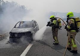 Bomberos en las labores de extinción del coche que ha ardido.