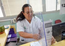 La celadora del Centro de Salud de San Roque retira el cartel del uso de mascarillas.