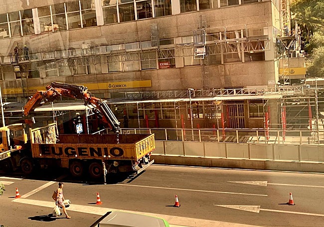 La grúa de Eugenio, ante el edificio Múltiples. Una mujer atraviesa con la compra.