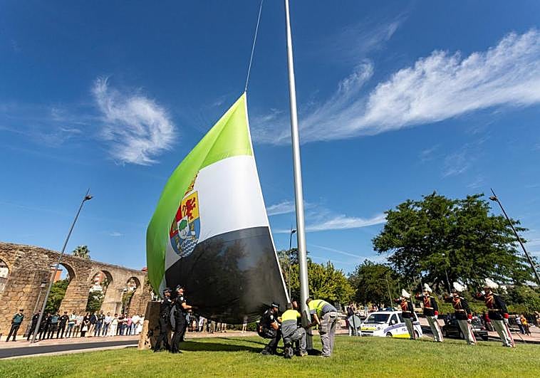 Trabajadores del Ayuntamiento y agentes de la Policía local colocan el estandarte en la glorieta.