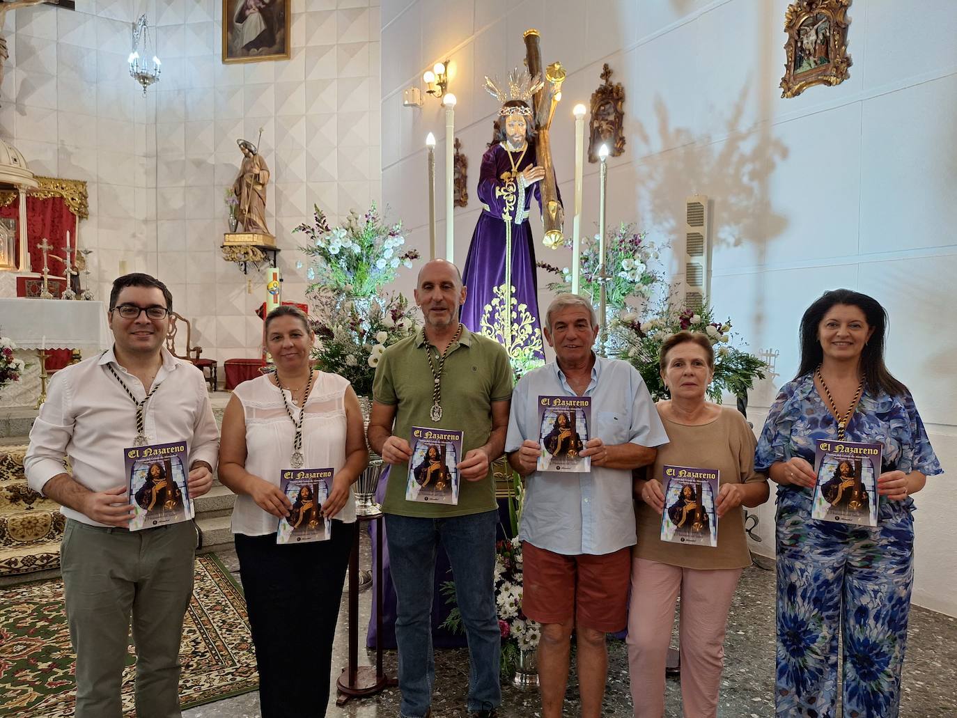 Algunos miembros de la Comisión de la Hermandad del Cristo con ejemplares de su nueva publicación, ayer ante su imagen titular.