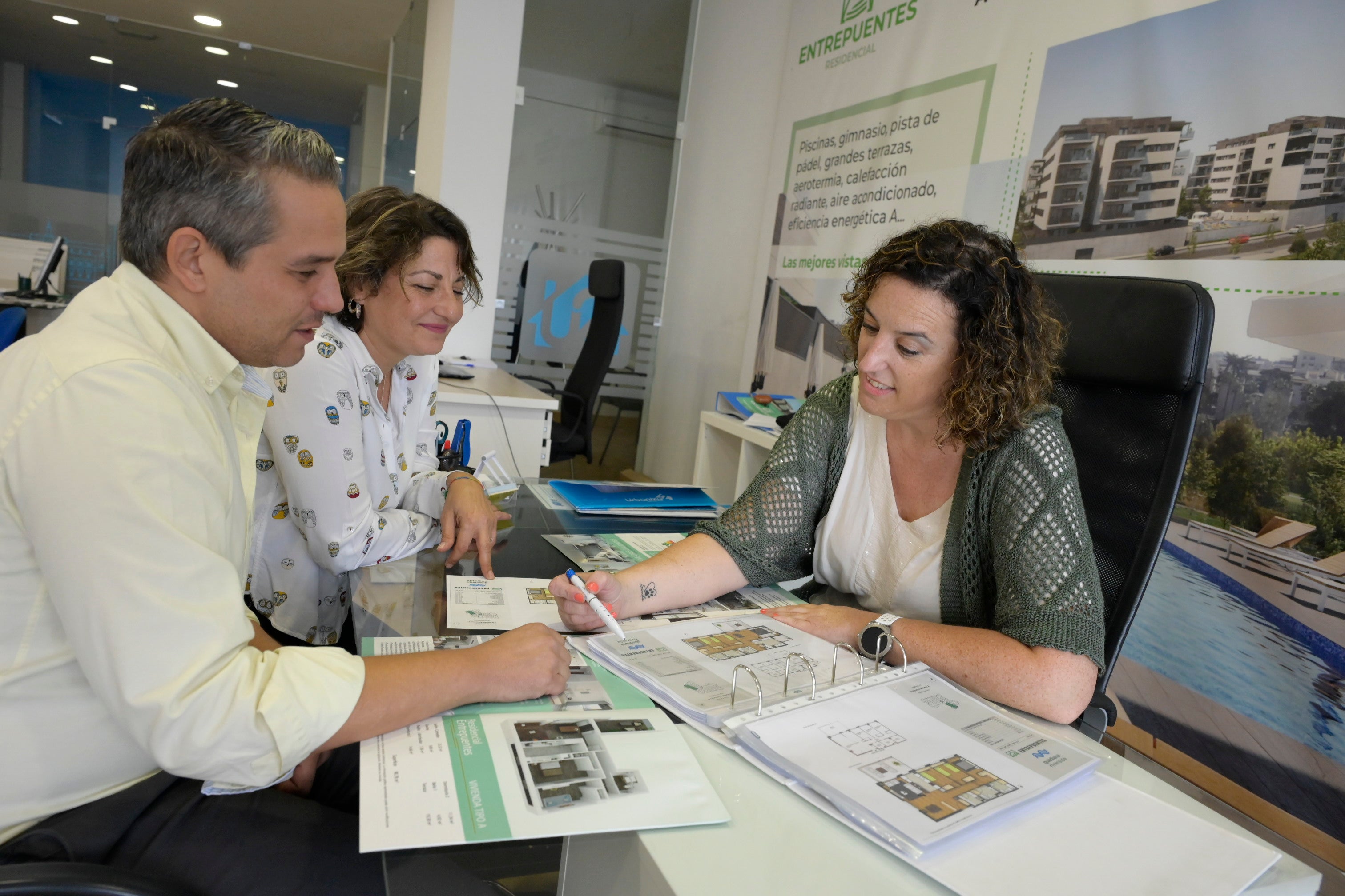 Cristina Alejandro muestra sobre plano viviendas a dos clientes que buscan alquilar un piso.